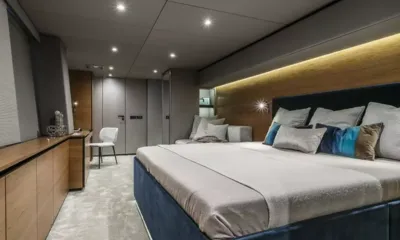 7X: Cabin with large double bed, blue headboard, wooden dresser and lit wood panel