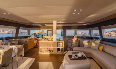 Adriatic Dragon: Geräumiger Salon mit geschwungenem Sofa, Bar, Esstisch und Panoramafenstern bei Sonnenuntergang