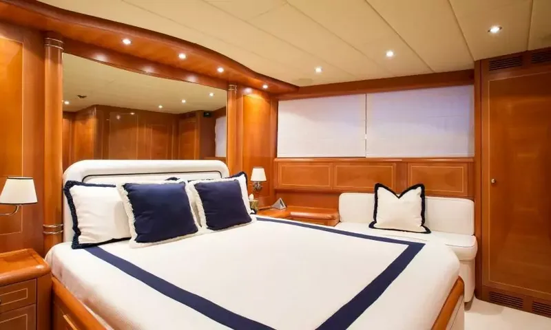 Allure: Cabine dupla com roupa de cama branca com acabamento azul-marinho, espelho e sofá pequeno