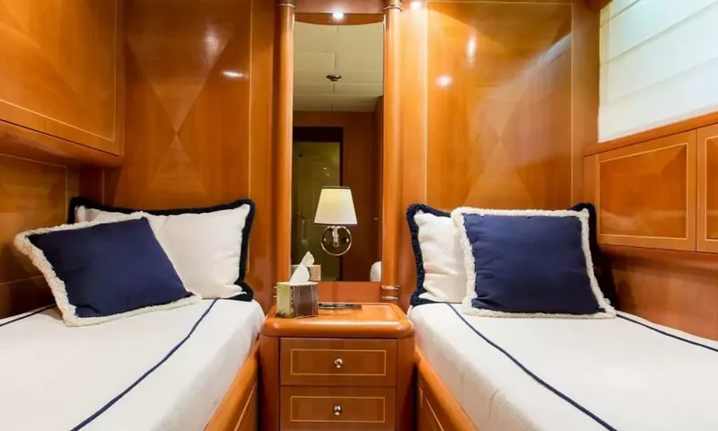 Allure: Cabine com duas camas de solteiro, almofadas azul-marinho e mesa de cabeceira entre elas