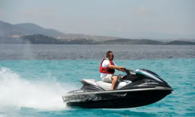 Amaya: Uomo con giubbotto di salvataggio su una moto d'acqua nera su acqua turchese