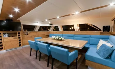 Anini: Indoor dining area with wooden table, blue chairs, a curved blue banquette and a television