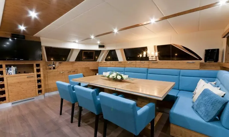 Anini: Indoor dining area with wooden table, blue chairs, a curved blue banquette and a television