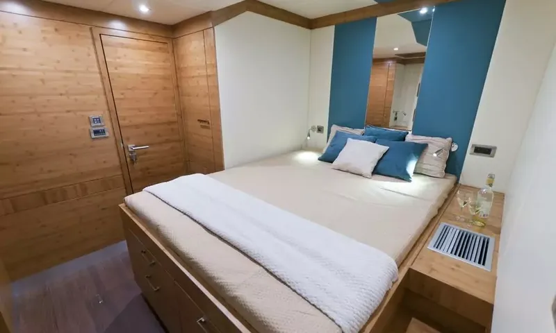 Anini: Guest cabin with double bed, blue cushions, wooden door and a mirrored blue wall
