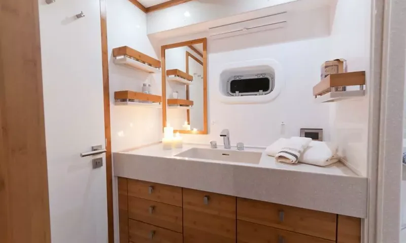Anini: Ensuite with stone counter sink, wooden drawers, mirror, shelves, candles and a porthole