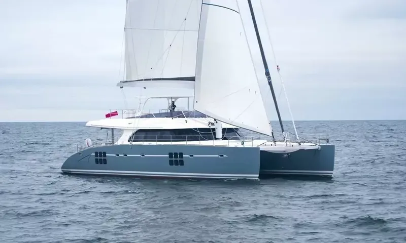 Anini: Grey hulled sailing catamaran under full sail on a choppy sea beneath an overcast sky