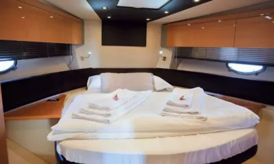 Atlantis 5: Cabine de proa com uma cama grande, toalhas dobradas, armários de madeira e vigias