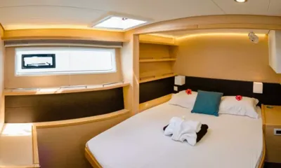 Diva: Double cabin with white bed, towels, flowers, shelves and hull window