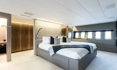 Beachouse: Cabine espaçosa com cama de casal central, manta preta e uma fileira de janelas no casco
