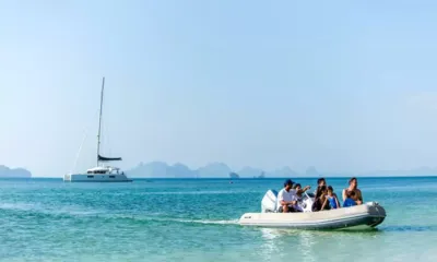 Blue Moon: Family riding an inflatable tender across shallow turquoise water with the catamaran anchored behind