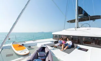 Blue Moon: Family relaxing on forward lounge cushions beside a paddleboard and inflatable kayak on the nets