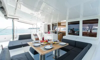 Blue Moon: Outdoor dining table laid with plates and fruit on the aft cockpit overlooking the sea