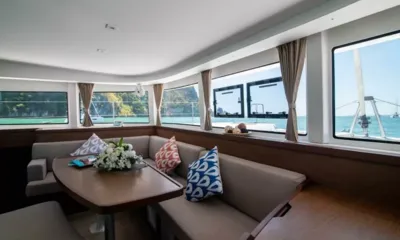 Cloud Dancer: Salão claro com sofá em L, mesa e janelas panorâmicas para a baía