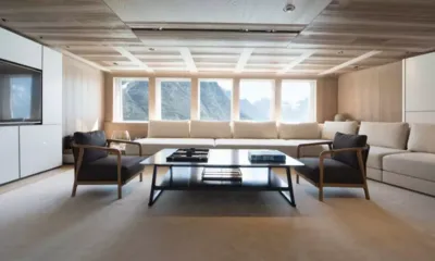 Cloudbreak: Salão luminoso com sofá creme comprido sob as janelas, duas poltronas e uma mesa de centro
