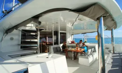 Senso: Família comendo à mesa no deck de popa sombreado com vista para o mar