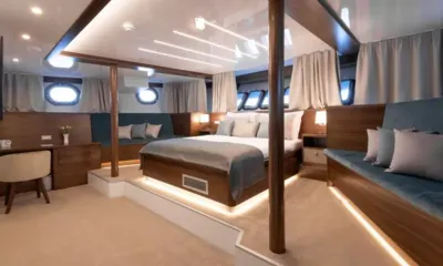 Corsario: Cabina spaziosa con letto matrimoniale rialzato, divani blu, scrivania e oblò