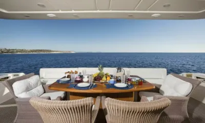 Day Off: Table du pont arrière dressée pour le petit déjeuner avec fruits, chaises en osier et vue dégagée sur la mer