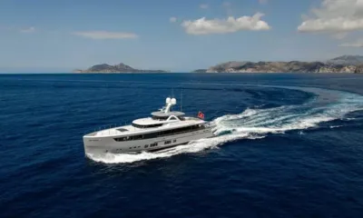 Delta One: Yacht turning at speed on open blue sea with islands in the distance
