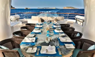 Deniki: Mesa longa posta para o jantar no deck de popa com a esteira e as ilhas ao fundo