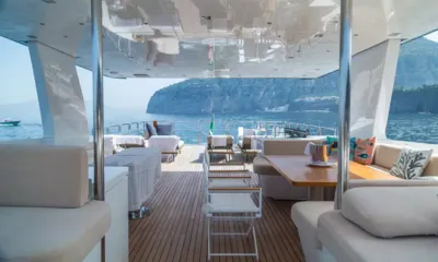 Don Michele: ソファ、ダイニングテーブル、椅子、サンベッドが海岸に面して並ぶ、日陰の後部デッキ