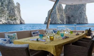 Don Michele: 海に立つ高い岩の柱に面した、グラスとナプキンが並ぶ屋外のテーブル
