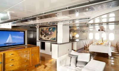 Dwinger: Salón luminoso con sofá blanco, televisión sobre un mueble de madera y mesa de comedor puesta