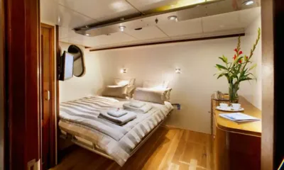 Dwinger: Camarote doble con ropa de cama a rayas, toallas dobladas, televisión y una cómoda de madera