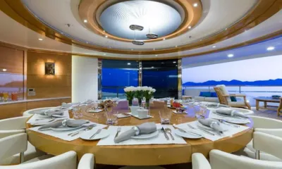 Galaxy: Mesa redonda posta para o jantar com tulipas brancas, abrindo para um deck com vista para o mar ao entardecer
