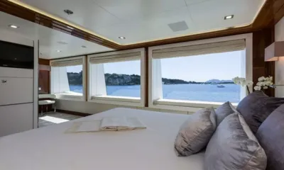 Galaxy: Cama de frente para amplas janelas com vista para águas calmas e uma costa rochosa