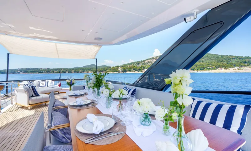 Getaway: Outdoor table laid with plates, glasses and white flowers overlooking a calm bay