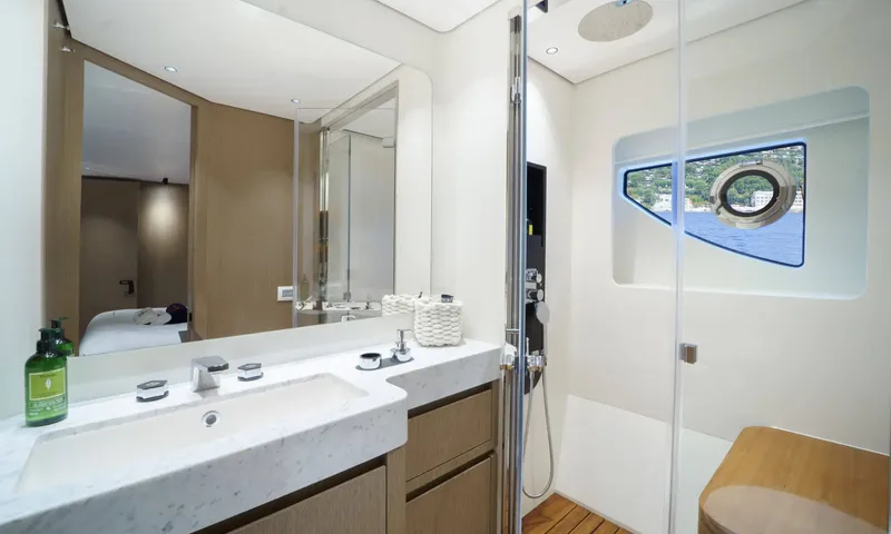Getaway: Ensuite with marble basin, mirror and glass shower beside a porthole window