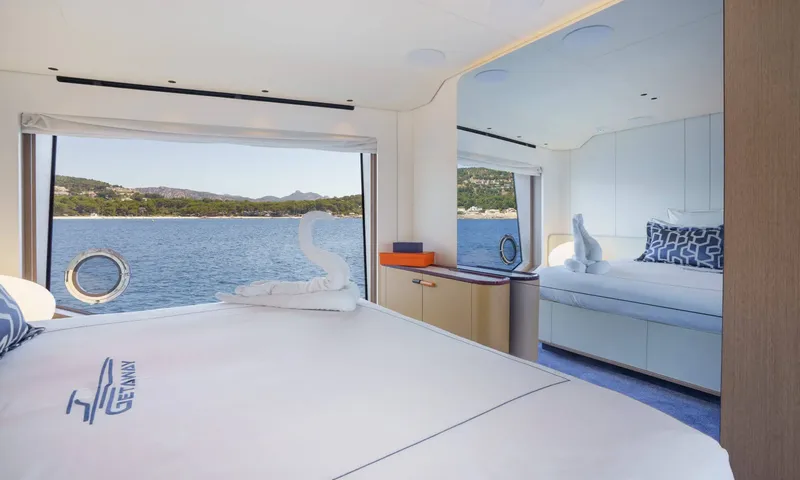 Getaway: Cabin with a large bed facing a wide window onto the sea and a towel swan