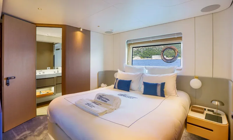 Getaway: Double cabin with blue cushions, rolled towels and a porthole window over the bed