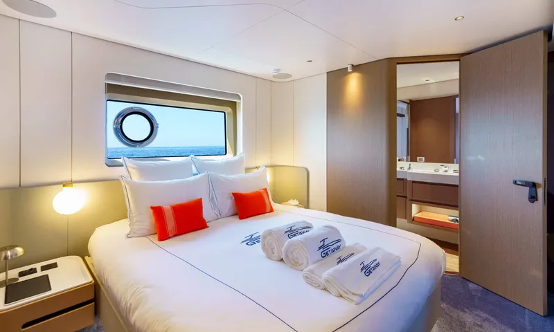 Getaway: Double cabin with orange cushions, rolled towels and an open door to the ensuite