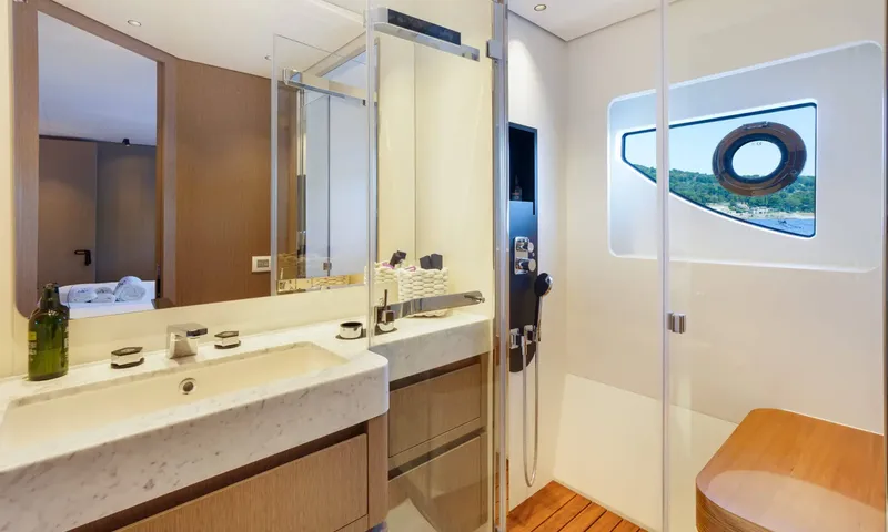 Getaway: Ensuite with marble basin, mirror and glass shower beside a porthole window