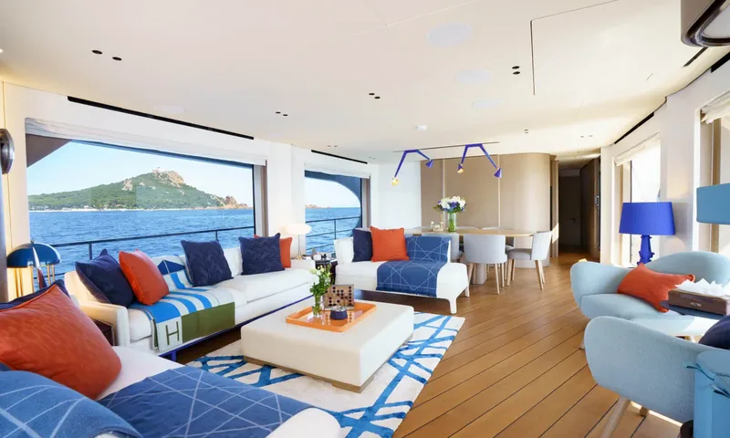 Getaway: Bright saloon with white sofas, blue and orange cushions and large windows facing the sea
