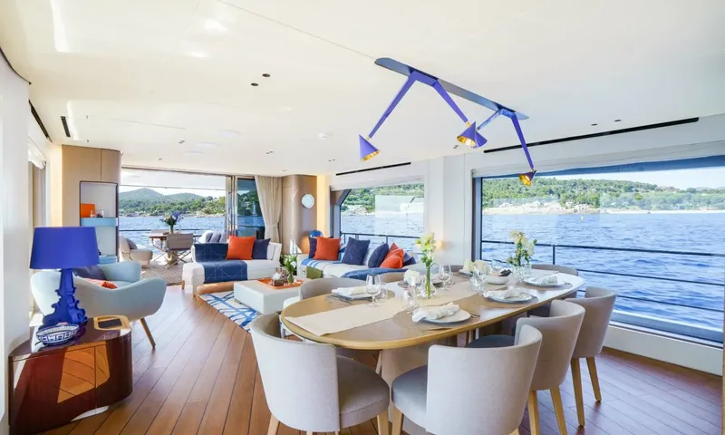 Getaway: Indoor dining table set for eight beside large windows, with the lounge area behind