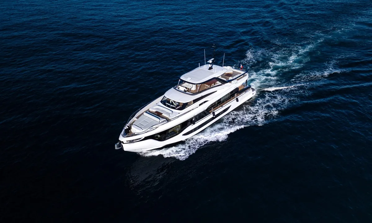 Getaway: White motor yacht cruising across deep blue sea, seen from above with a foaming wake