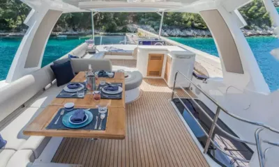 Hunky Dory Of: Flybridge com mesa de jantar de teca posta, sofás e posto de comando sob um hardtop