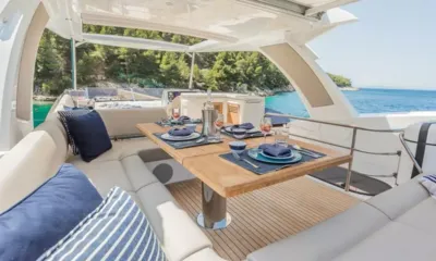 Hunky Dory Of: Mesa de jantar posta com assentos estofados no flybridge de frente para uma costa arborizada