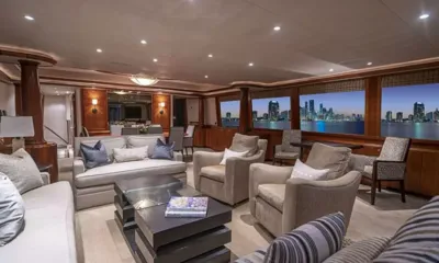Indigo II: Salão principal com sofás, poltronas e mesa de centro ao lado de janelas que mostram um horizonte urbano noturno