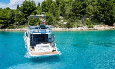 Jupika II: Vue arrière d'un yacht dans une eau turquoise près d'un rivage rocheux couvert de pins