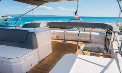 Jupika II: Flybridge avec assises à coussins gris, sol en teck et petite table face à la mer