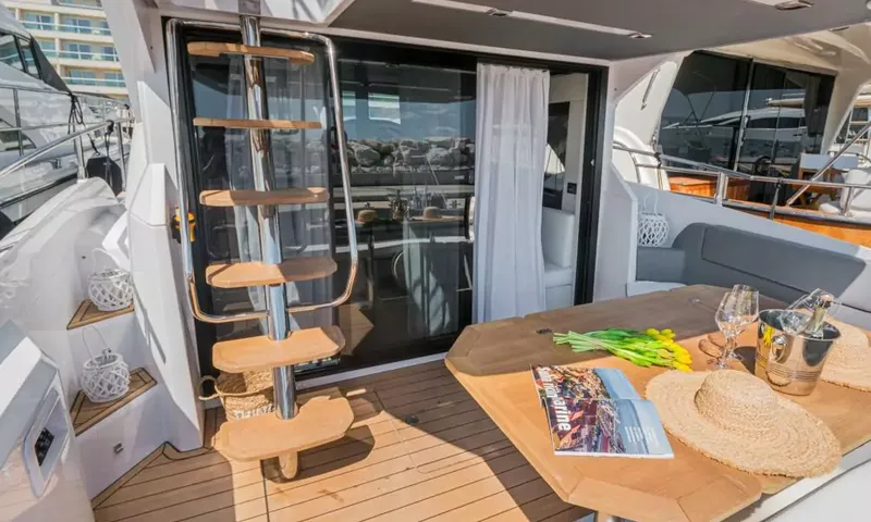 Jupika II: Pont arrière avec table en teck, chapeau de paille, seau à champagne et échelle vers le flybridge