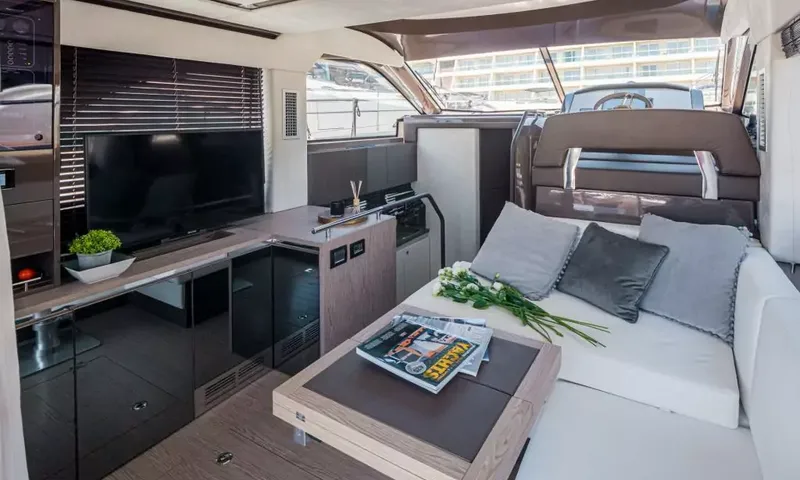 Jupika II: Salon avec canapé blanc, coussins gris, table basse, télévision et poste de pilotage au fond
