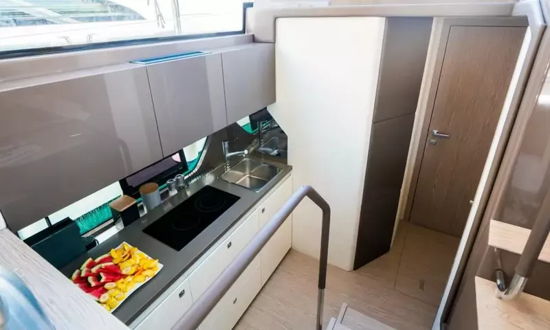Jupika II: Vue plongeante sur la cuisine avec plaque de cuisson, évier, plateau de fruits et une porte de cabine