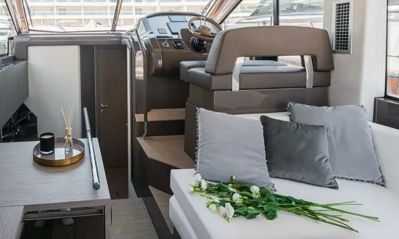 Jupika II: Canapé du salon avec coussins gris et fleurs à côté du siège du poste de pilotage inférieur