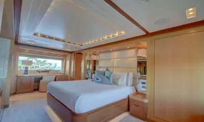 Kaos: Double bed with padded headboard, desk under a window and wood paneled walls