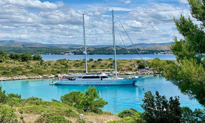 Lady Gita: Voilier à deux mâts au mouillage dans une baie turquoise bordée de pins