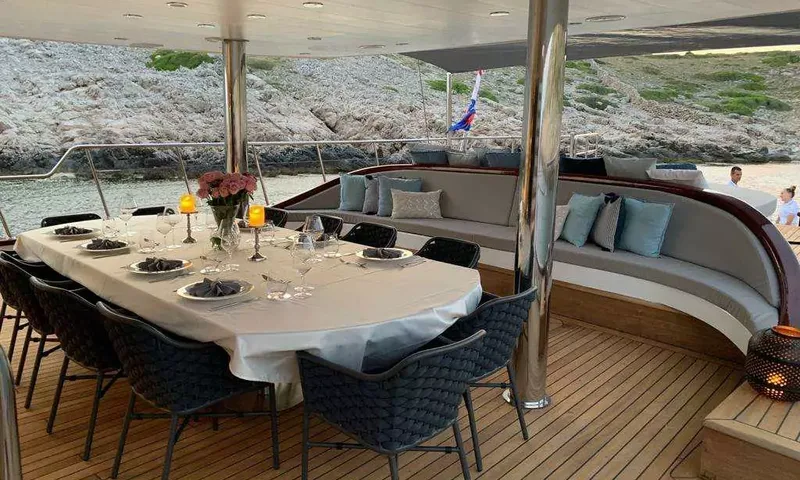 Lady Gita: Table à manger sur le pont arrière couvert, ornée de bougies et de fleurs, près d'un canapé courbe